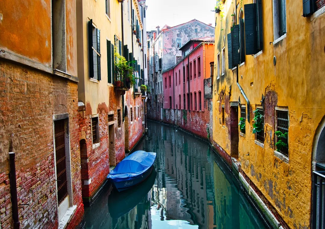 Vieux canal vénitien avec bâtiments colorés et bateau en Italie, vue pittoresque et charmante d'une ville historique.